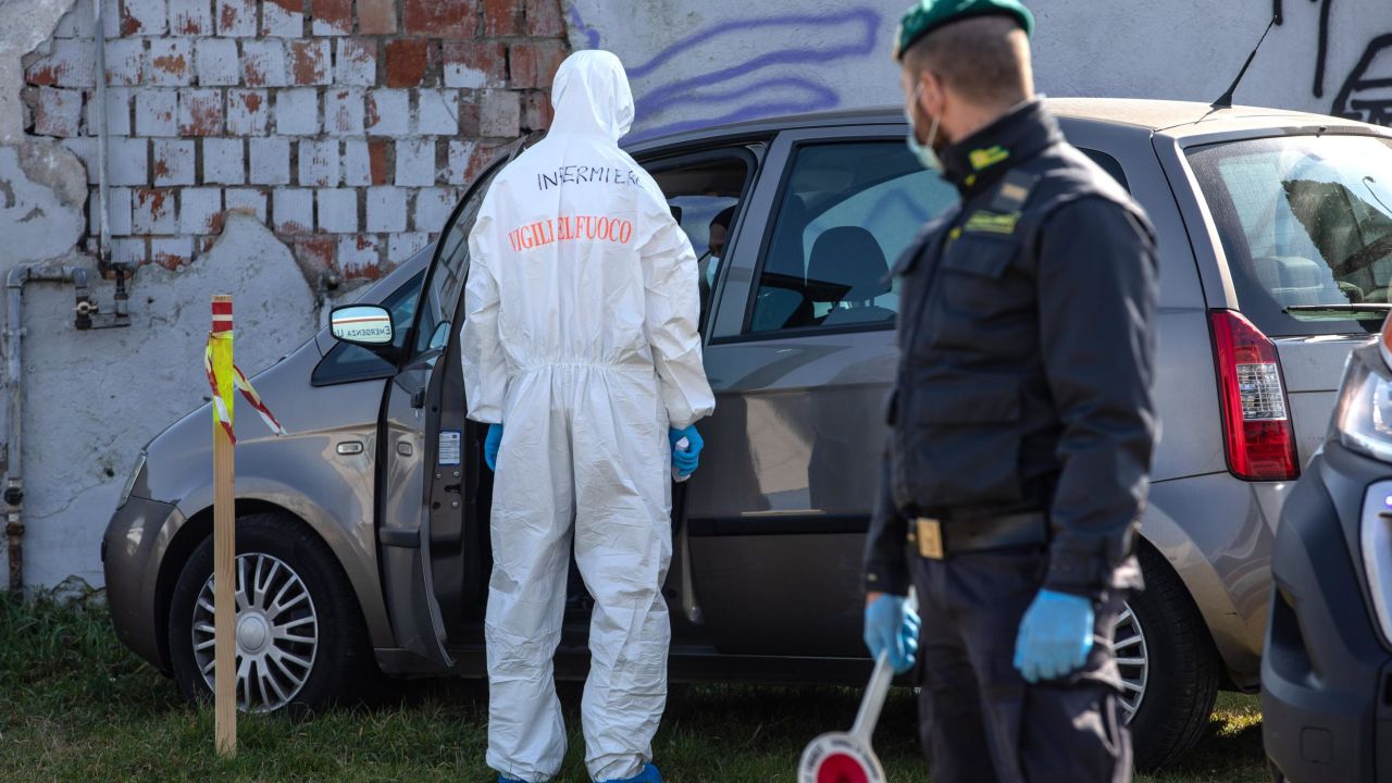 CASALPUSTERLENGO, ITALY - FEBRUARY 24: A rescue worker, wearing a protective suit, checks the medical conditions of a man who tried to reach a hospital driving his own car but was eventually stopped by Italian Guardia di Finanza (Custom Police) officers at a road block on February 24, 2020 in Casalpusterlengo, south-west Milan, Italy. Casalpusterlengo is one of the ten small towns placed under lockdown after coronavirus sparked infections throughout the Lombardy region. Italy is the last country to be hit hard by the virus with five dead and more than 224 infected as of today. The spread marks Europe's biggest outbreak, prompting Italian Government to issue draconian safety measures. (Photo by Emanuele Cremaschi/Getty Images)