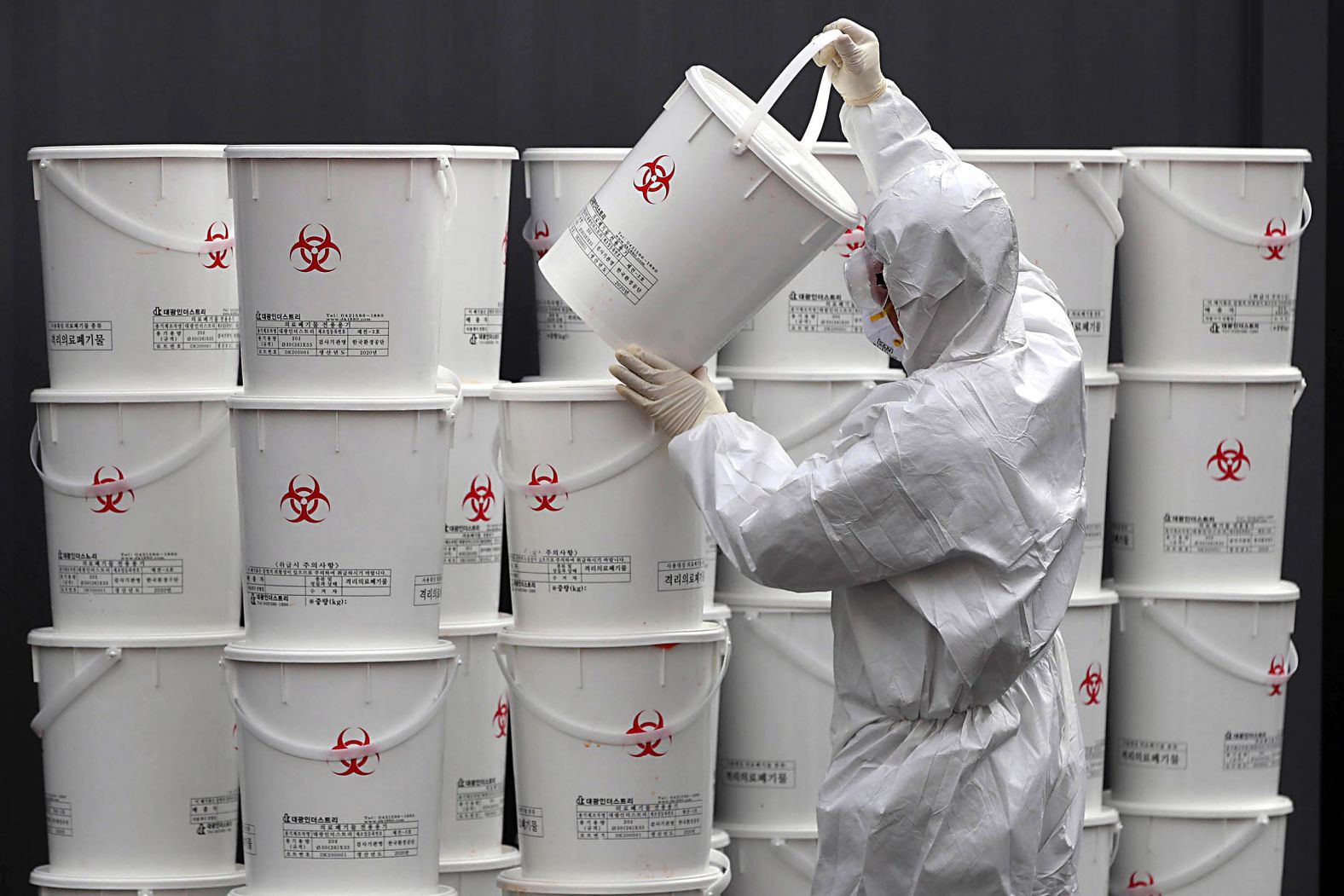 A worker in Daegu, South Korea, stacks plastic buckets containing medical waste from coronavirus patients.