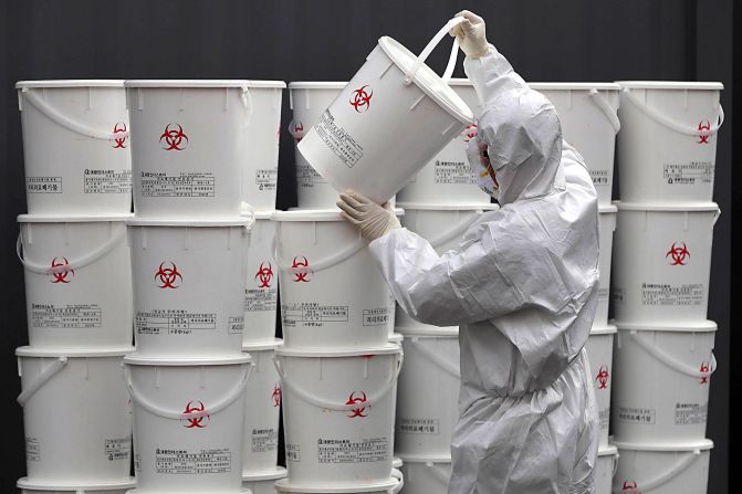 A worker in Daegu, South Korea, stacks plastic buckets containing medical waste from coronavirus patients.