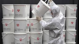 A worker in protective gear stacks plastic buckets containing medical waste from coronavirus patients at a medical center in Daegu, South Korea, Monday, Feb. 24, 2020. South Korea reported another large jump in new virus cases Monday a day after the the president called for "unprecedented, powerful" steps to combat the outbreak that is increasingly confounding attempts to stop the spread. (Lee Moo-ryul/Newsis via AP)