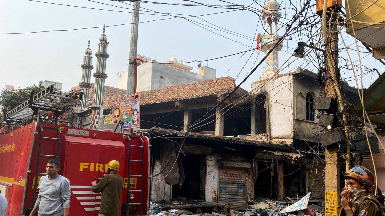 Firefighters (L) stand near a burnt-out mosque and shops following clashes between people supporting and opposing a contentious amendment to India's citizenship law in New Delhi on February 26, 2020. - Four more people have died in some of the worst sectarian violence in decades in New Delhi, a hospital source told AFP, which takes the death toll from several days of rioting to 17. (Photo by Sajjad HUSSAIN / AFP) (Photo by SAJJAD HUSSAIN/AFP via Getty Images)