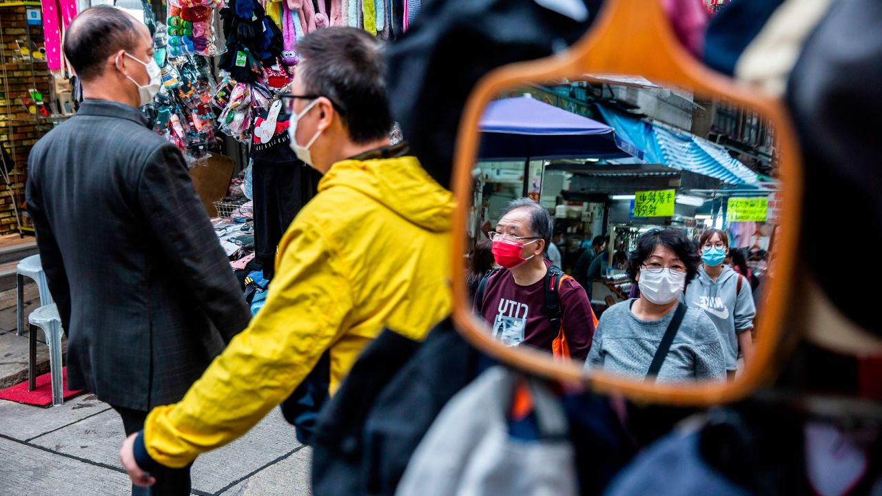 People wearing face masks walk through a Hong Kong market on February 25, 2020. 