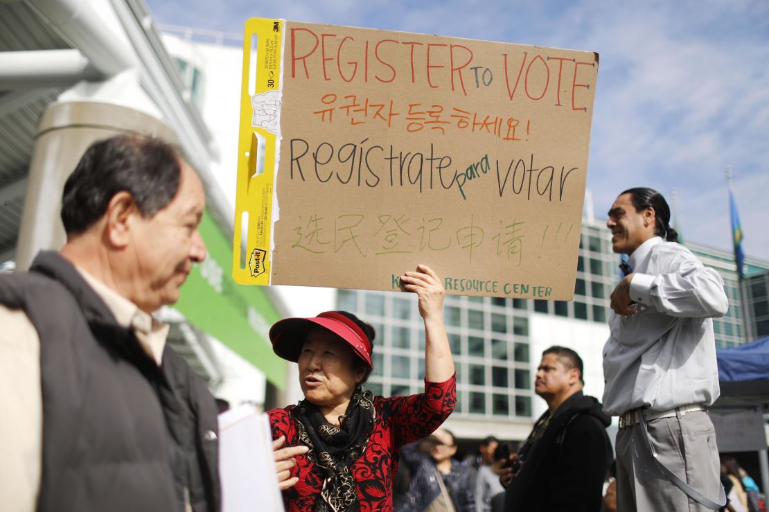 A canvasser holds a sign encouraging people to register to vote following a naturalization ceremony on March 20, 2018 in Los Angeles.