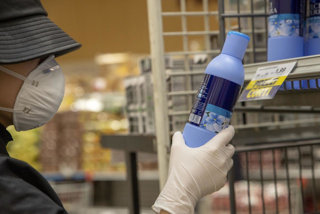 A customer wearing a protective face mask and gloves reads a cleaning product label in a grocery store in Milan, Italy, on February 25. Italian authorities are now scrambling to respond to the outbreak, after the prime minister was forced to admit that a hospital had mishandled the region's first coronavirus case and had contributed to the virus' spread.