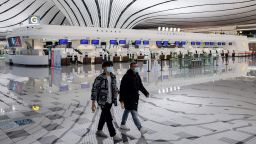 This picture taken on February 14, 2020 shows two men wearing face masks walking through a nearly empty terminal at Daxing international airport in Beijing, as travel has ground to a halt in the wake of the the COVID-19 coronavirus outbreak. (Photo by NICOLAS ASFOURI / AFP) (Photo by NICOLAS ASFOURI/AFP via Getty Images)