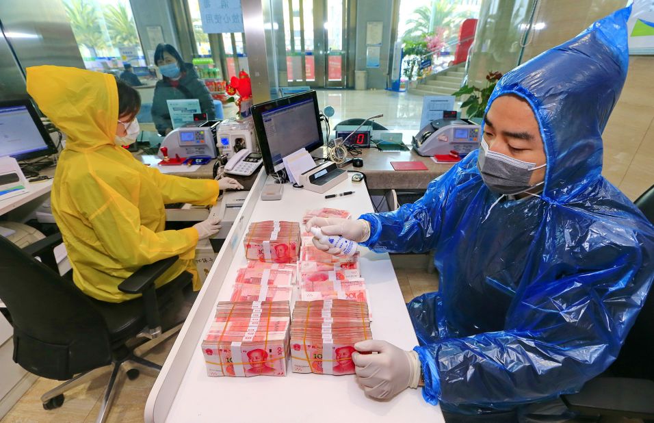 A bank clerk disinfects banknotes in China's Sichuan province on February 26, 2020.