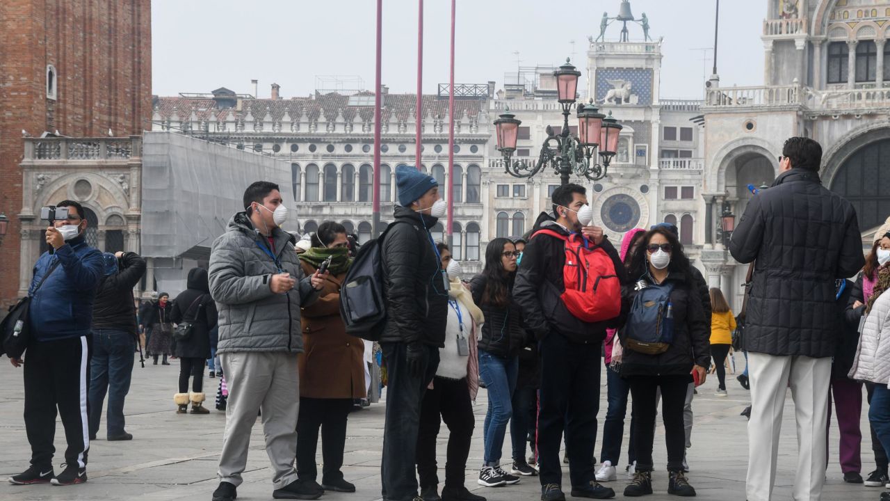 Tourists wearing protective masks visit Venice on February 25, 2020, during the usual period of the Carnival festivities which have been cancelled following an outbreak of the COVID-19 novel coronavirus in northern Italy. - Italy's new coronavirus spread south on February 25 to Tuscany and Sicily, as the civil protection agency reported a surge in the number of infected people and Rome convened emergency talks. (Photo by ANDREA PATTARO / AFP) (Photo by ANDREA PATTARO/AFP via Getty Images)