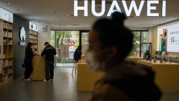 A pedestrian wearing a protective mask walks past a Huawei store in a shopping mall on February 27, 2020 in Shanghai, China.