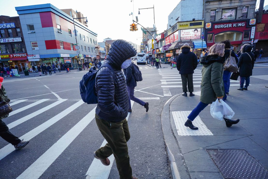 People wear protective masks to fend off the coronavirus, while street vendors peddlel hand sanitizer and other disinfecting products in Queens, New York.