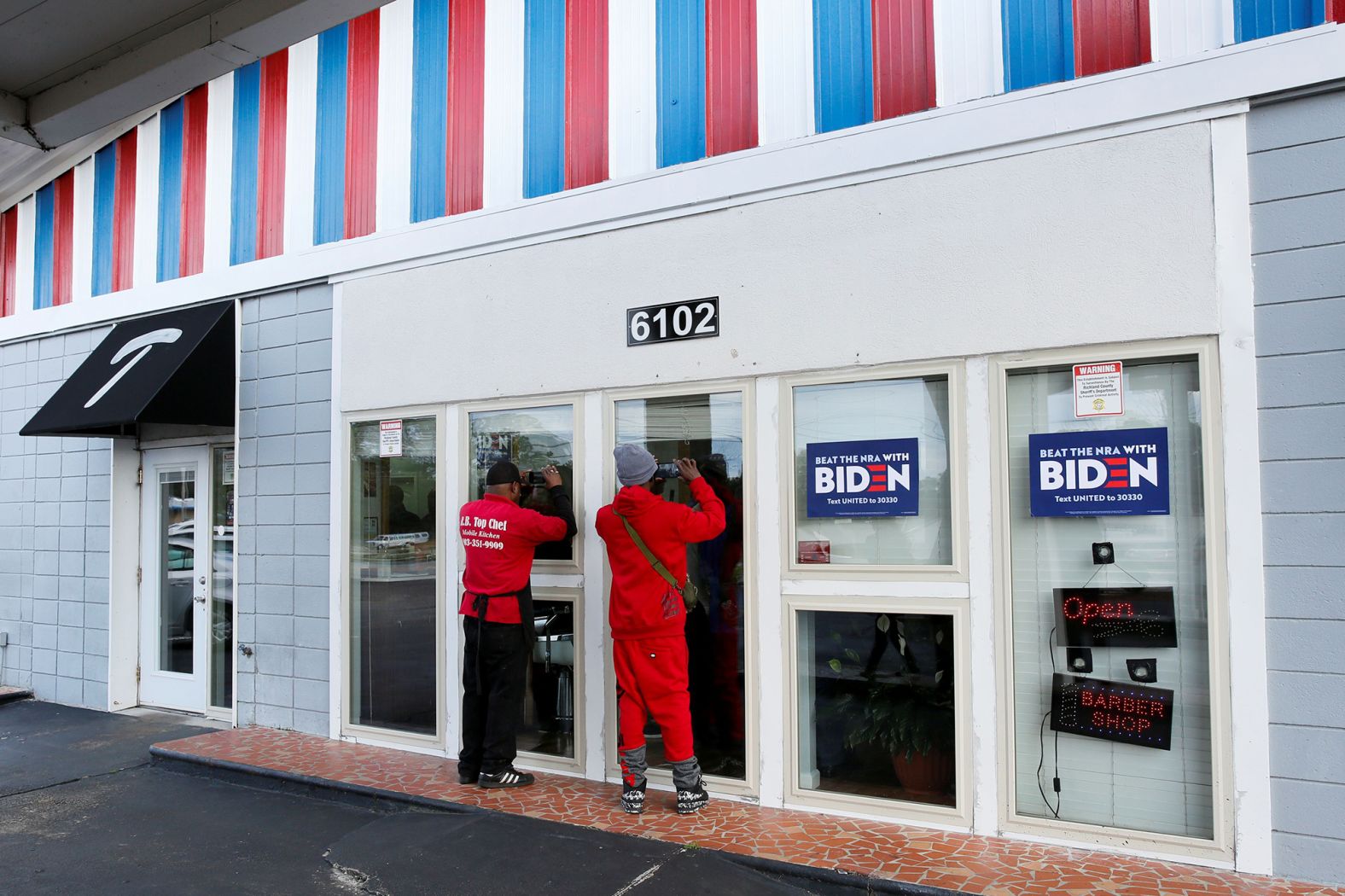 People take photos of Biden through the windows of Toliver's Mane Event, a barbershop in Columbia.