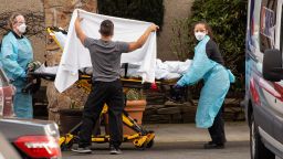 Healthcare workers transport a patient on a stretcher into an ambulance at Life Care Center of Kirkland. Dozens of staff and residents at Life Care Center of Kirkland are reportedly exhibiting coronavirus-like symptoms.