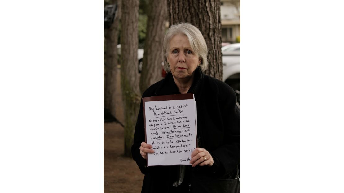 Bonnie Holstad holds a sign expressing concerns for her husband Ken Holstad, a resident at Life Care Center of Kirkland.