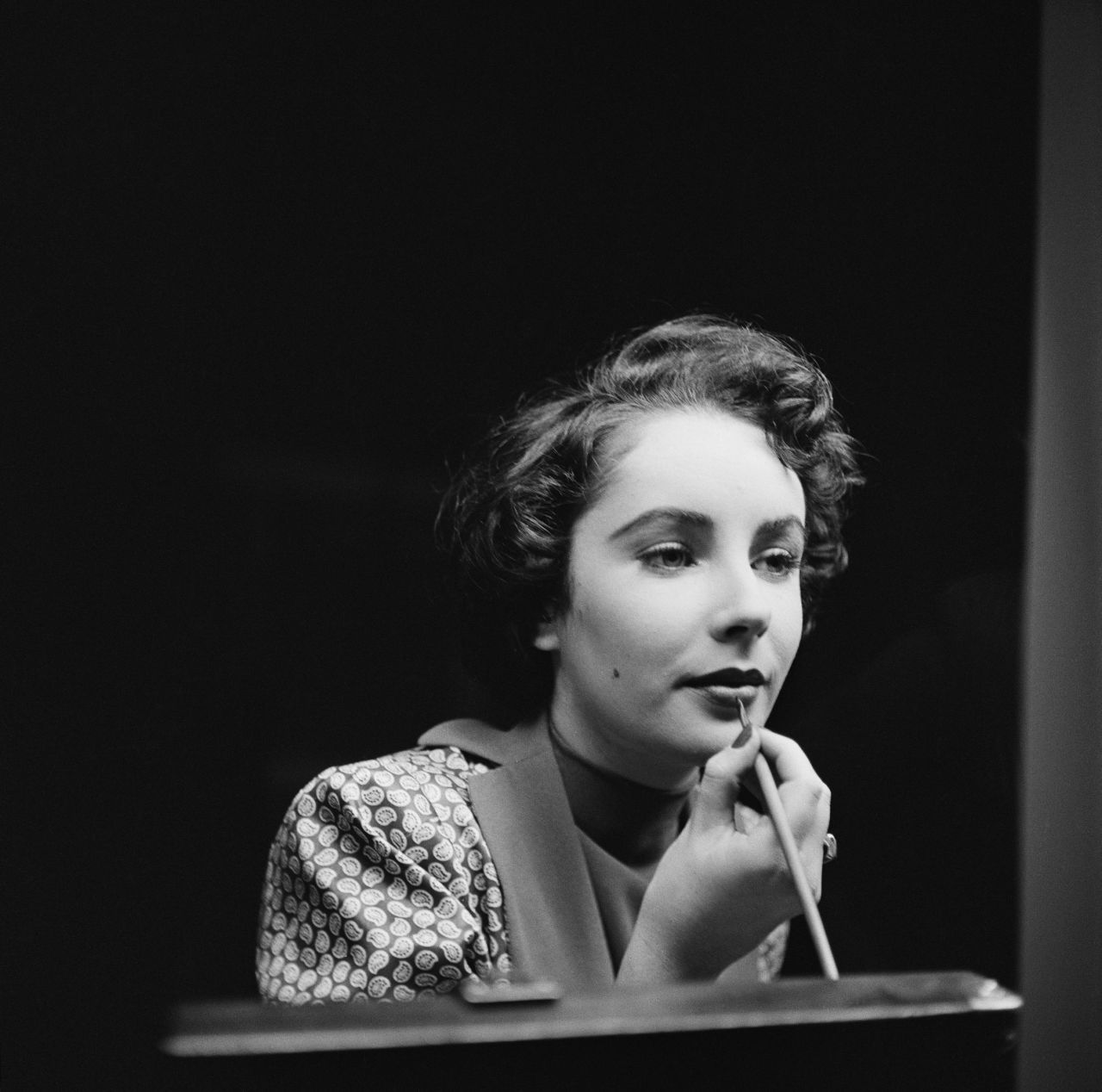 Actress Elizabeth Taylor touches up her lipstick (1948)