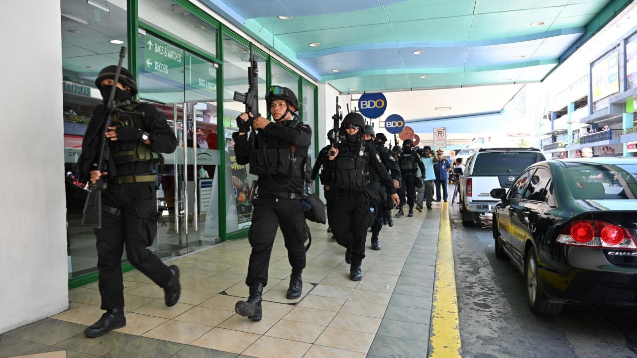 Members of a police SWAT team take positions outside one of the entrances to a mall after a hostage situation was reported in suburban Manila.