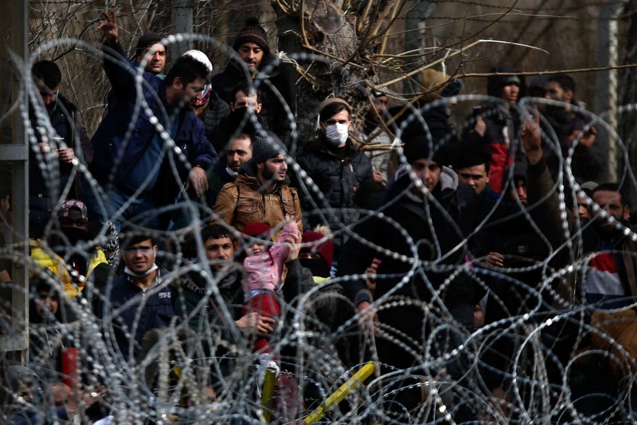 Migrants stand behind a fence at Turkey's border with Greece on Monday, March 2.