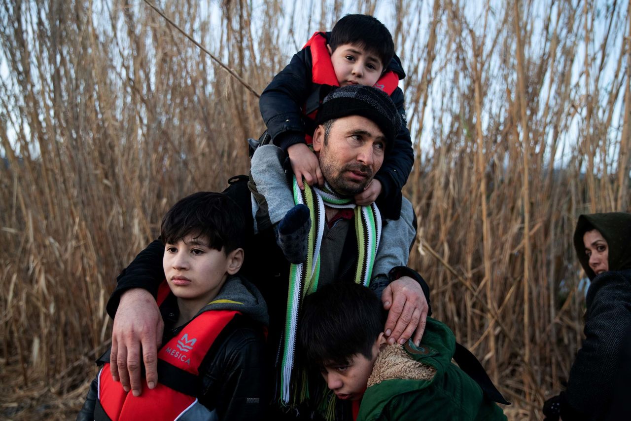 A man holds his three sons as migrants arrive on a dinghy March 2 near the Greek village of Skala Sikamias. They had crossed from Turkey to the island of Lesbos.
