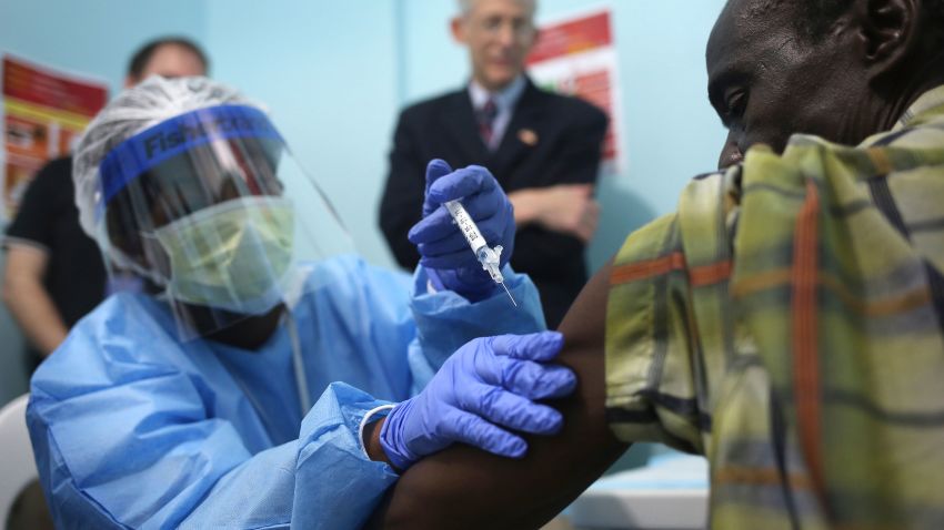 A nurse administers an injection on the first day of the Ebola vaccine study being conducted at Redemption Hospital, formerly an Ebola holding center, on February 2, 2015 in Monrovia, Liberia. Twelve people were given injections Monday, out of a planned 27,000 people in the Monrovia area. The clinical research study is being conducted jointly by the U.S. National  Institutes of Health (NIH), and the Liberian Ministry of Health. The Ebola epidemic virus has killed at least 3,700 people in Liberia alone, the most of any country, and nearly 9,000 across in West Africa. In background of photo is Dr. Clifford Lane, Clinical Director of the U.S. National Institute for Allergy and Infectious Diseases.