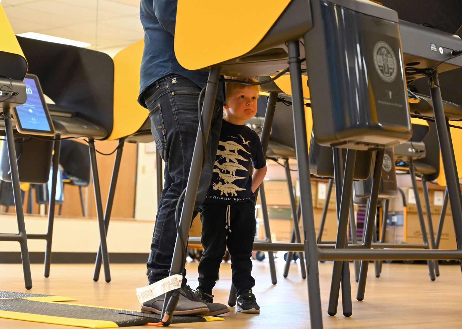 Bennett Stuart looks out from under a voting booth as his father casts an early ballot in Burbank, California, on Monday.