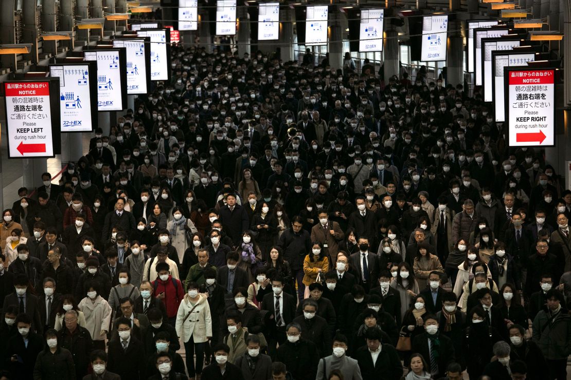 A large crowd wearing masks commutes through Shinagawa Station in Tokyo, Tuesday, March 3, 2020. 