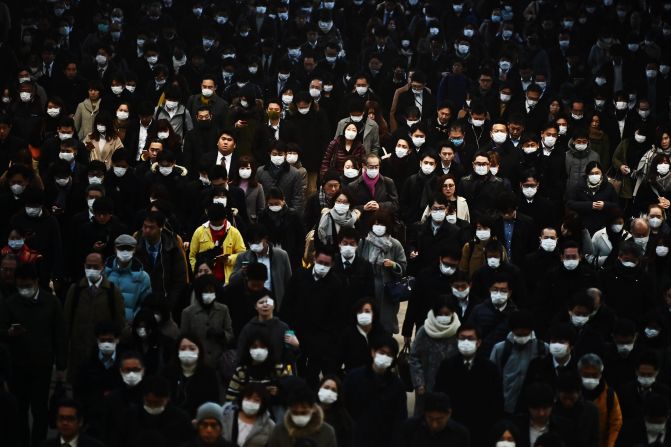 Commuters wearing masks make their way to work during morning rush hour at the Shinagawa train station in Tokyo.