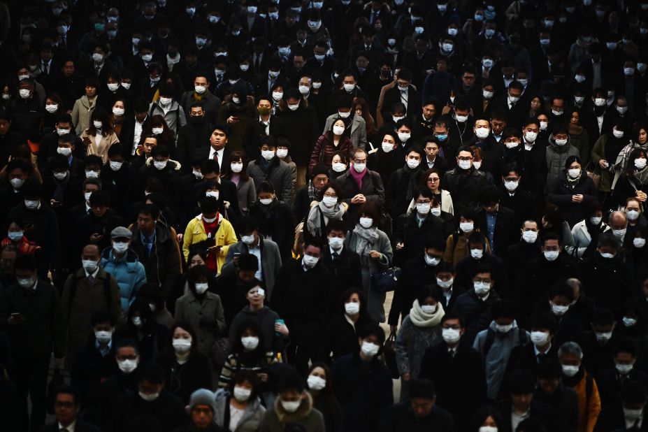 Commuters wearing masks make their way to work during morning rush hour at the Shinagawa train station in Tokyo on February 28.