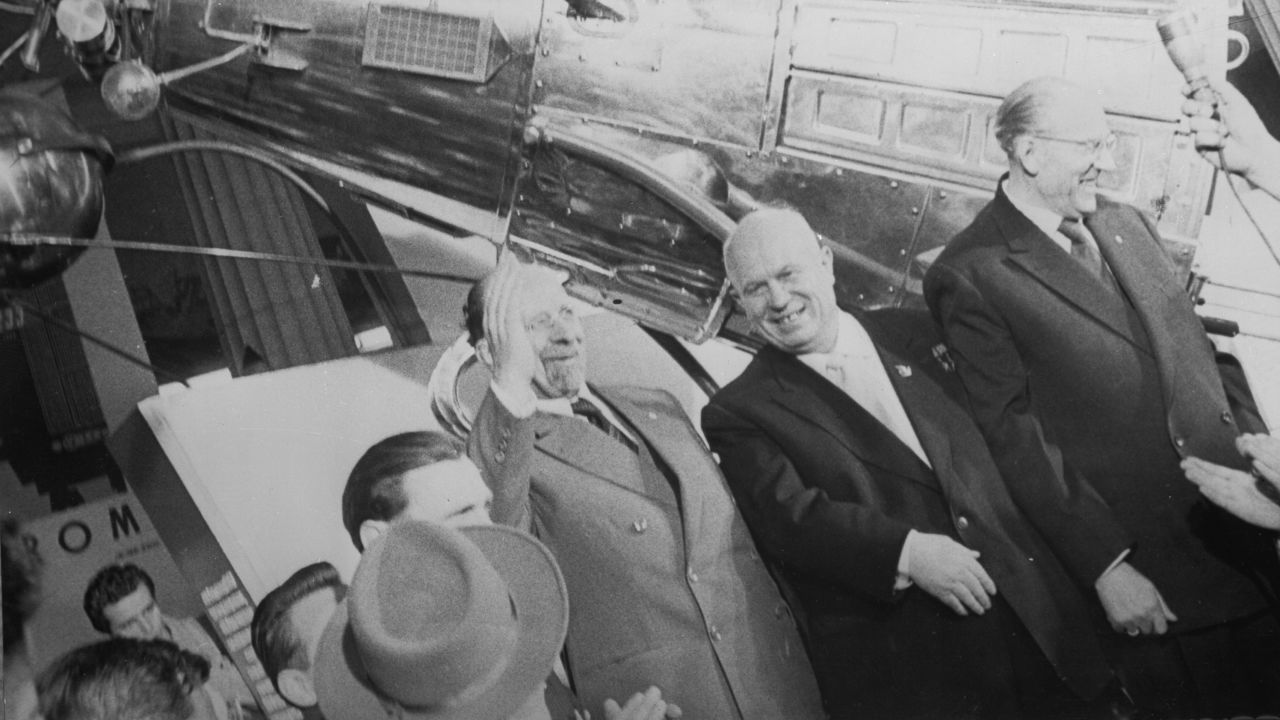 Nikita Khrushchev, center, who led the Soviet Union during the first part of the Cold War, stands in front of a model of Sputnik III.