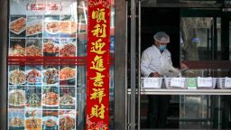An employee wearing protective gear reads a newspaper at a restaurant only offering take-out orders following the coronavirus outbreak in Beijing, Sunday, March 1, 2020. 
