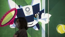 TOKYO, JAPAN - FEBRUARY 26: A pedestrian wearing a face mask walks past a display with an illustration of the 2020 Tokyo Olympic and Paralympic Games mascot character Miraitowa on February 26, 2020 in Tokyo, Japan. Concerns that the Tokyo Olympics may be postponed or cancelled are increasing as Japan confirms 862 cases of Coronavirus (COVID-19) and as some professional sporting contests are being called off or rescheduled and some major Japanese corporations ask for people to work from home. (Photo by Tomohiro Ohsumi/Getty Images)