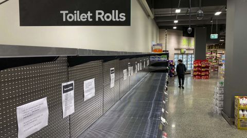A shopper passes empty shelves usually stocked with toilet paper in Melbourne, Australia, on March 5.