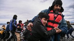 TOPSHOT - A man helps a young boy to walk after a dinghy with 54 Afghan refugees landed ashore the Greek island of Lesbos on February 28, 2020. - Turkey will no longer close its border gates to refugees who want to go to Europe, a senior official told AFP on February 28, shortly after the killing of 33 Turkish soldiers in an airstrike in northern Syria. (Photo by ARIS MESSINIS / AFP) (Photo by ARIS MESSINIS/AFP via Getty Images)