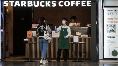 An employee checks the temperature of a customer at the entrance of Starbucks in Shanghai.