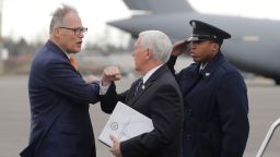 Vice President Mike Pence, center, greets Washington Gov. Jay Inslee, left, as Pence arrives, Thursday, March 5, 2020 at Joint Base Lewis-McChord in Washington state. Officials are avoiding handshakes due to the COVID-19 coronavirus. (AP Photo/Ted S. Warren)