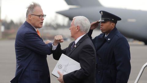 Vice President Mike Pence, center, greets Washington Gov. Jay Inslee, left, as Pence arrives on Thursday, March 5, at Joint Base Lewis-McChord in Washington state. Officials are avoiding handshakes due to the novel coronavirus.