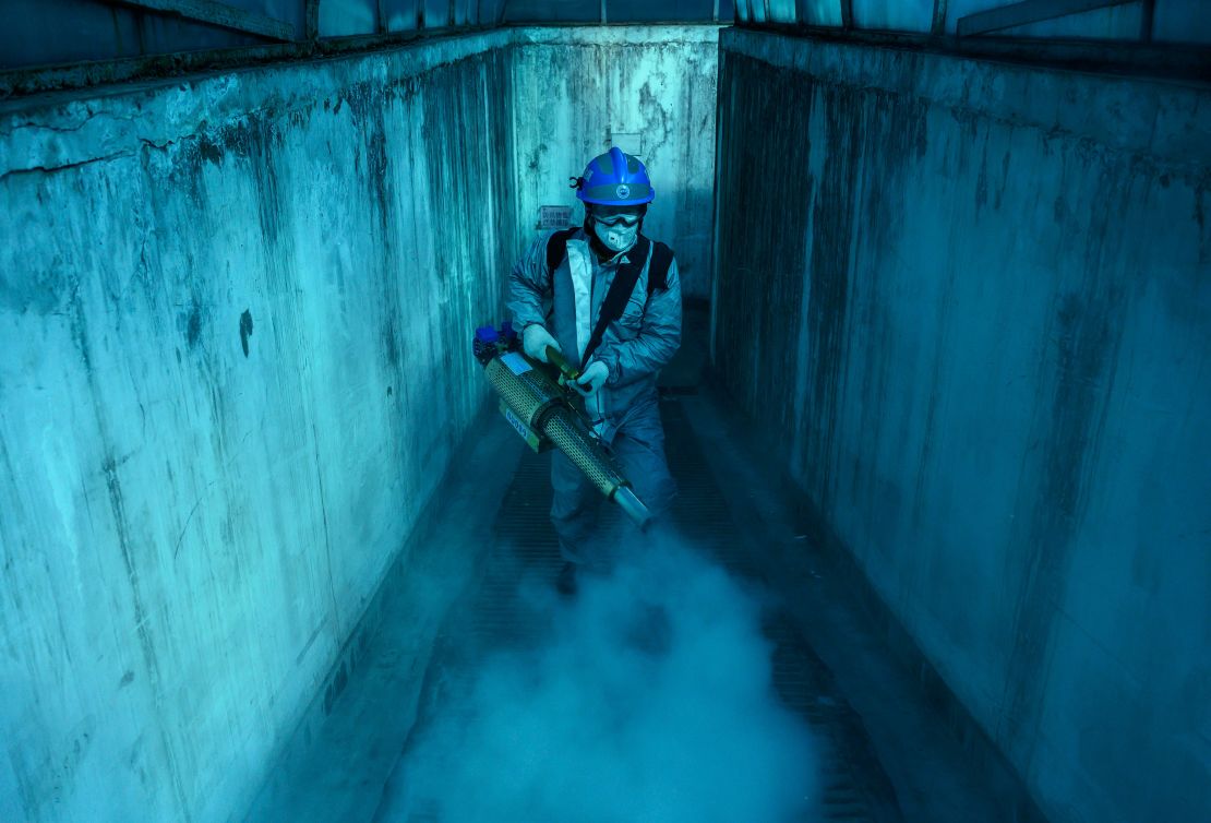 A volunteer wears a protective suit as he uses fumigation equipment to disinfect common areas of a local residential compound on March 5, 2020, in Beijing, China. 