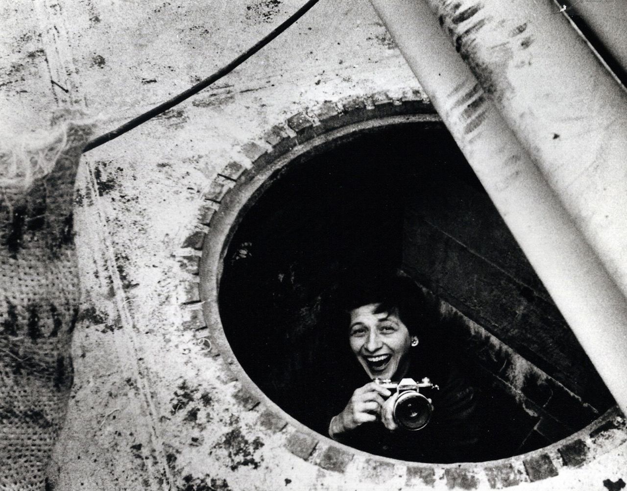 Charlotte Brooks stands inside a manhole in this photo from 1957. Brooks was the only female staff photographer at Look, a biweekly American magazine that highlighted general-interest stories from 1937 to 1971. At a time when many women were confined to softer news, Brooks covered the same issues that her male peers were covering, including politics and race. 