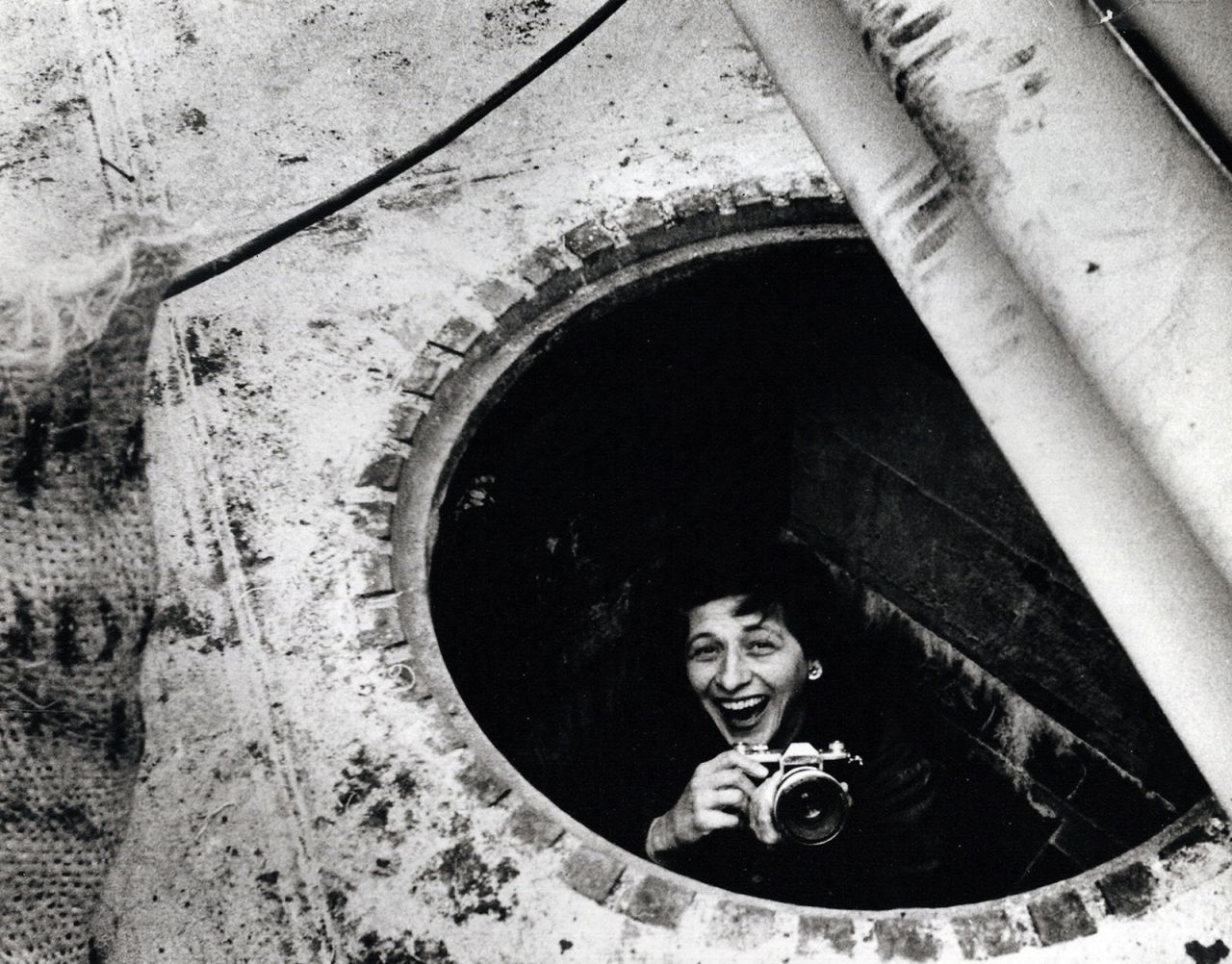 Charlotte Brooks stands inside a manhole in this photo from 1957. Brooks was the only female staff photographer at Look, a biweekly American magazine that highlighted general-interest stories from 1937 to 1971. At a time when many women were confined to softer news, Brooks covered the same issues that her male peers were covering, including politics and race.