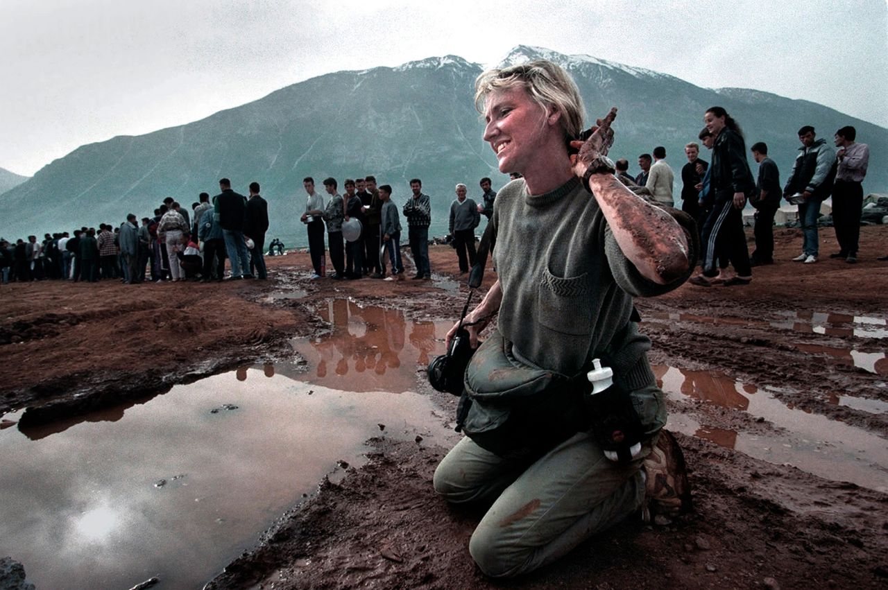 Carol Guzy is covered in mud as she photographs a bread line at a refugee camp in Kukes, Albania, in 1999. Guzy, a former Washington Post photographer, was the first journalist in history to win four Pulitzer Prizes. 