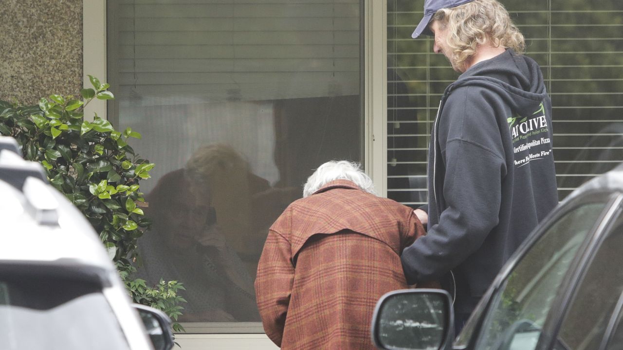 Charlie Campbell  takes his mom Dorothy Campbell, 88, to see her husband Gene Campbell, 89, through his room window at the Life Care Center nursing home in Kirkland, Washington. 