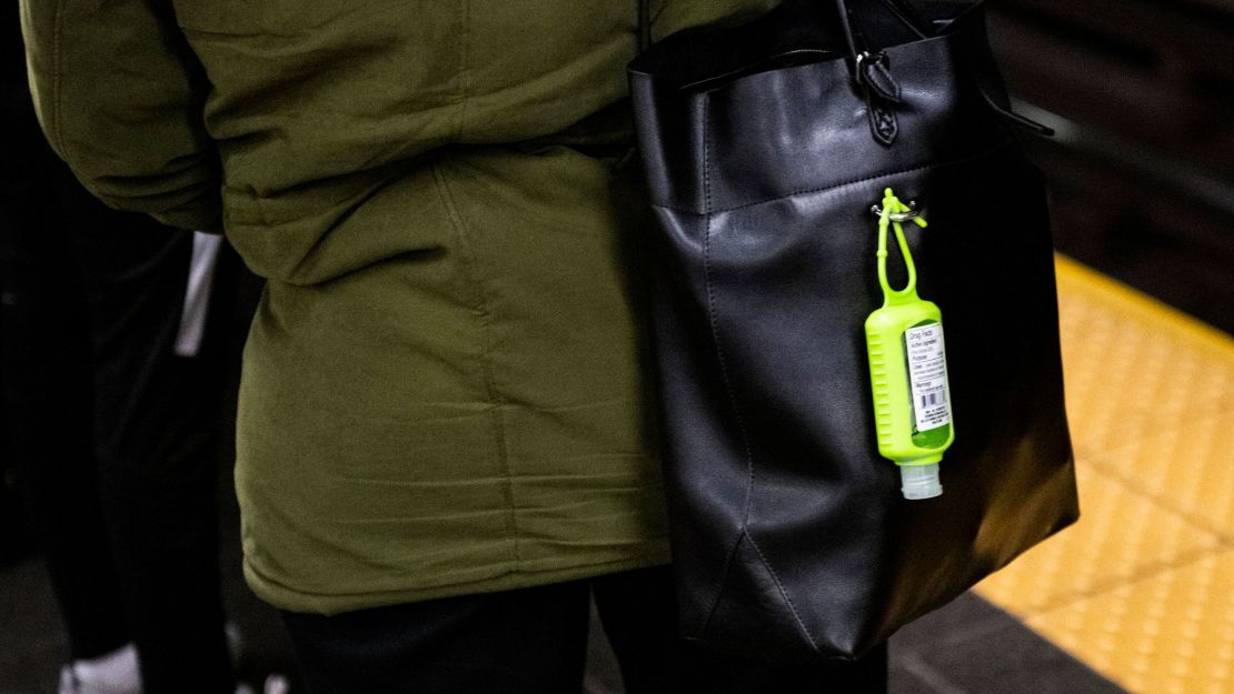 A hand sanitizer dispenser hangs from a subway rider's bag at the Times Square station in Manhattan.