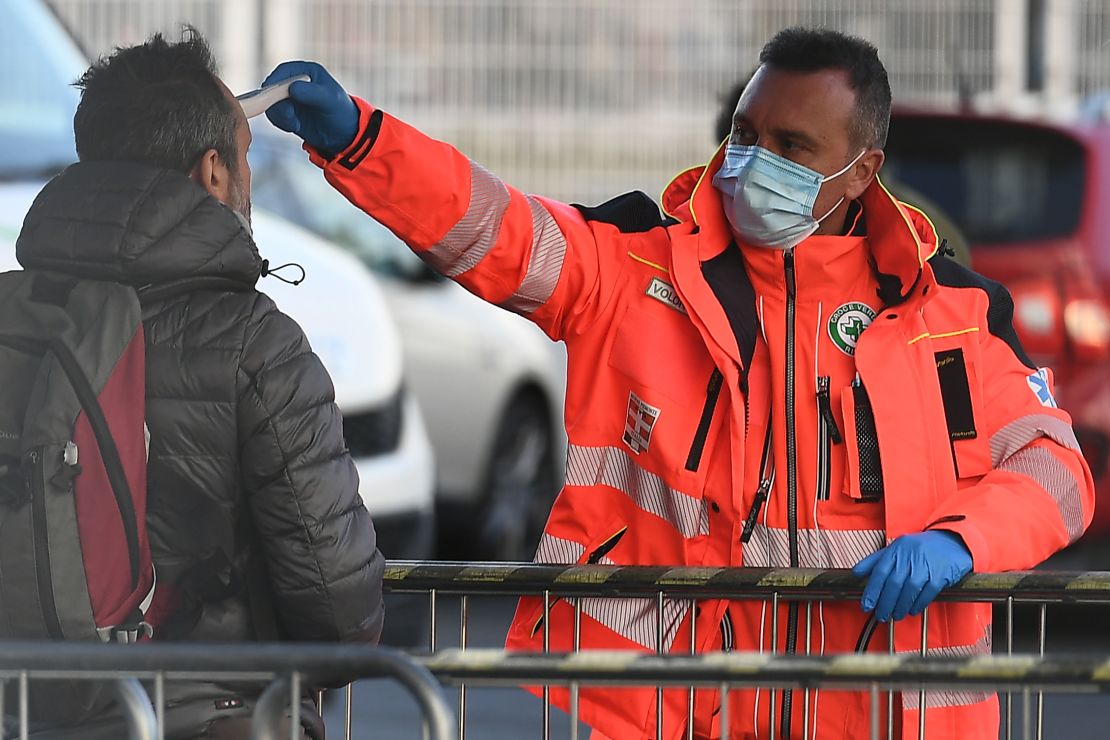 A health staff checks the body temperature of a man arriving at the stadium.