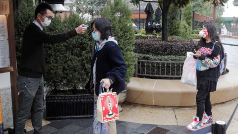 A staff member checks the body temperature of visitors outside Disneytown in Shanghai on Monday.