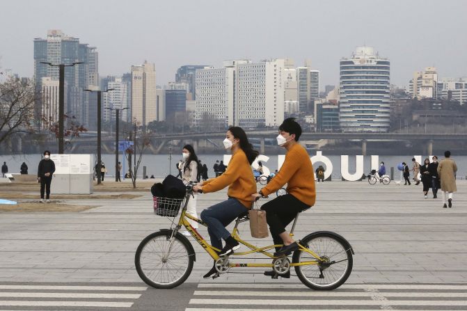 A couple rides a bicycle at a park in Seoul, South Korea, on March 7, 2020.
