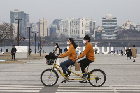 A couple rides a bicycle at a park in Seoul, South Korea, on March 7. 
