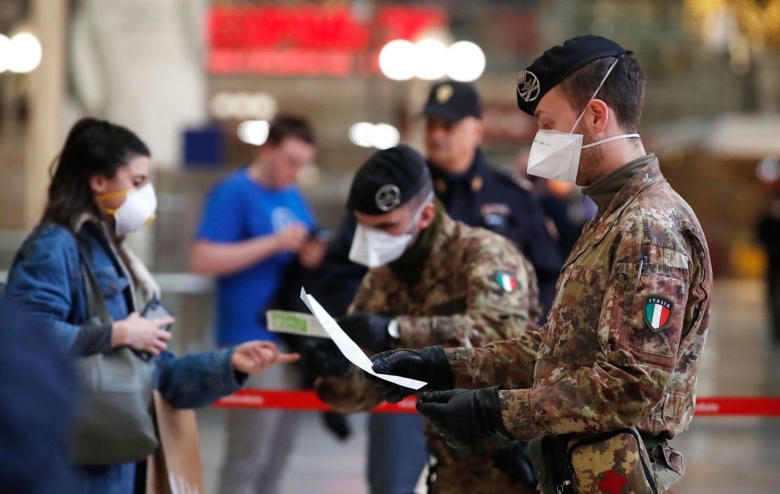 Police officers and soldiers check passengers leaving from Milan's main train station after travel was canceled except for work and health reasons.