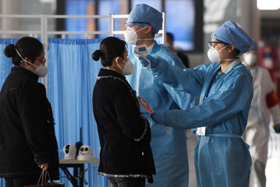 Workers wearing protective clothing check the temperatures of passengers entering the departures area at the Beijing Capital Airport on March 5.