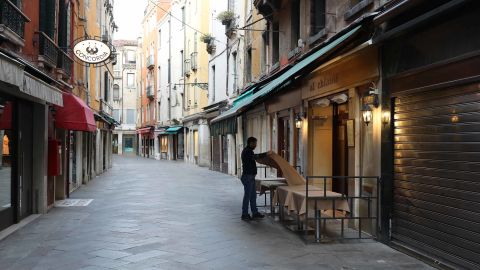 A waiter sets a table in a restaurant on an empty street in Venice, Italy. 