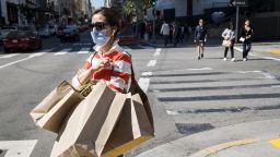 A pedestrian wearing a protective face mask carries shopping bags in San Francisco, California, U.S., on Wednesday, March 4, 2020. 