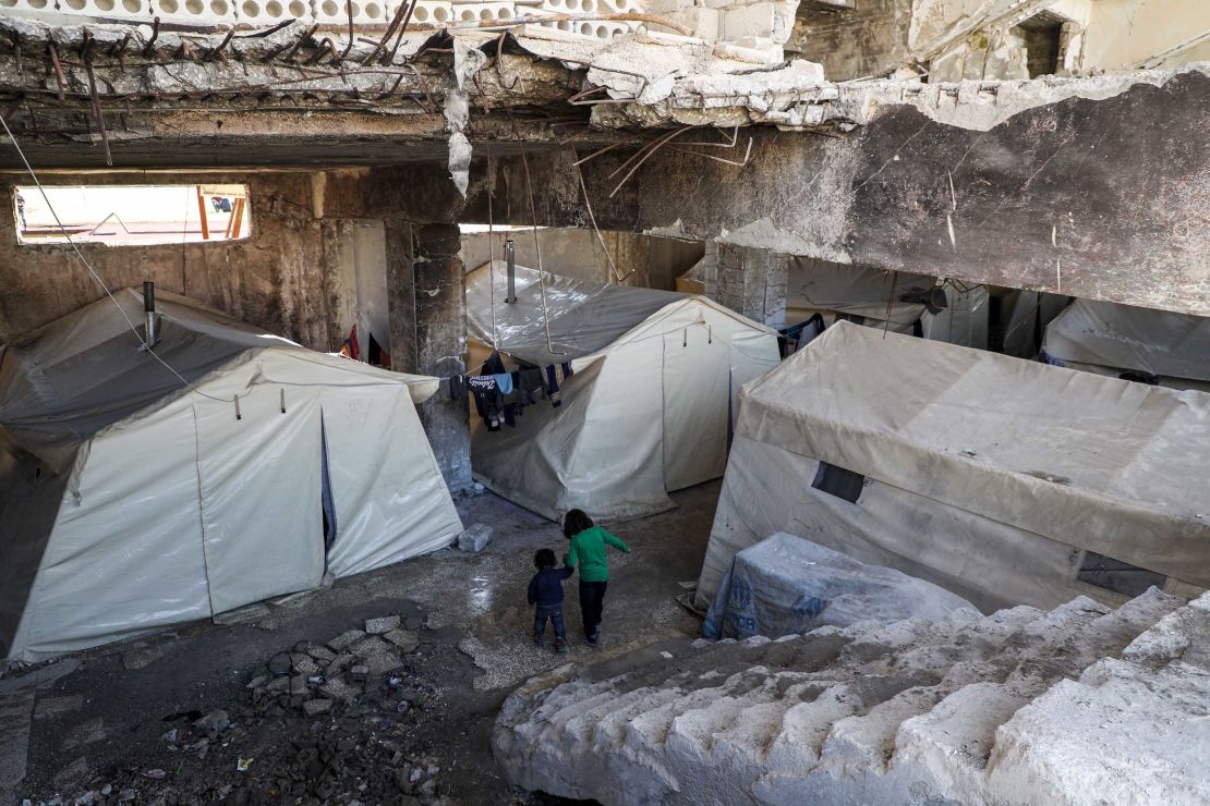 Syrian children displaced by the war walk at an underground makeshift camp at Idlib football stadium on March 3, 2020.