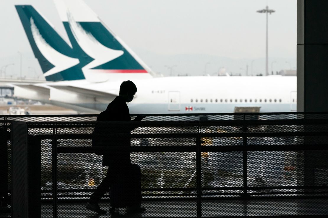A passenger wearing a face mask walks past Cathay Pacific aircraft parked at Kansai International Airport on Tuesday in Osaka, Japan.