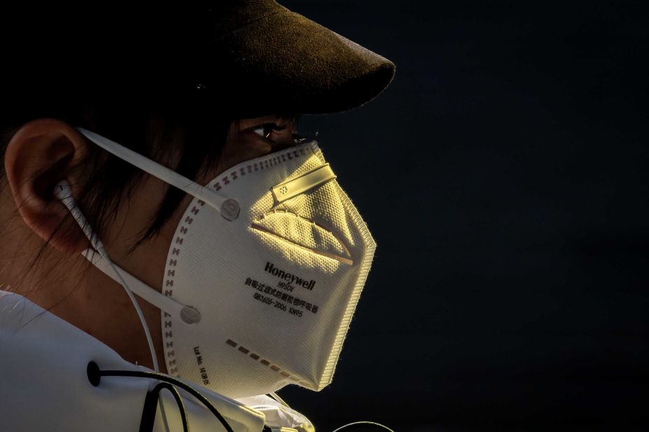 A person wearing a face mask walks outside of a shopping mall in Beijing on March 11, 2020.